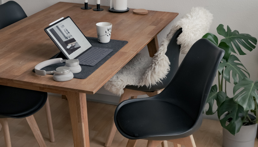Table with modern chairs, tablet computer with keyboard, headphones, and coffee mug.